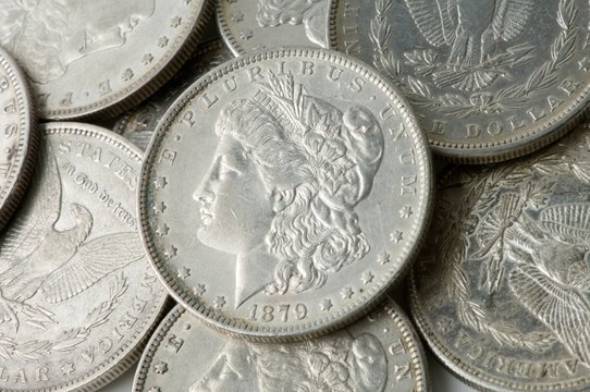 Collection of U.S. coins, prominently featuring an 1879 Morgan silver dollar with Lady Liberty's profile, surrounded by various other coins.