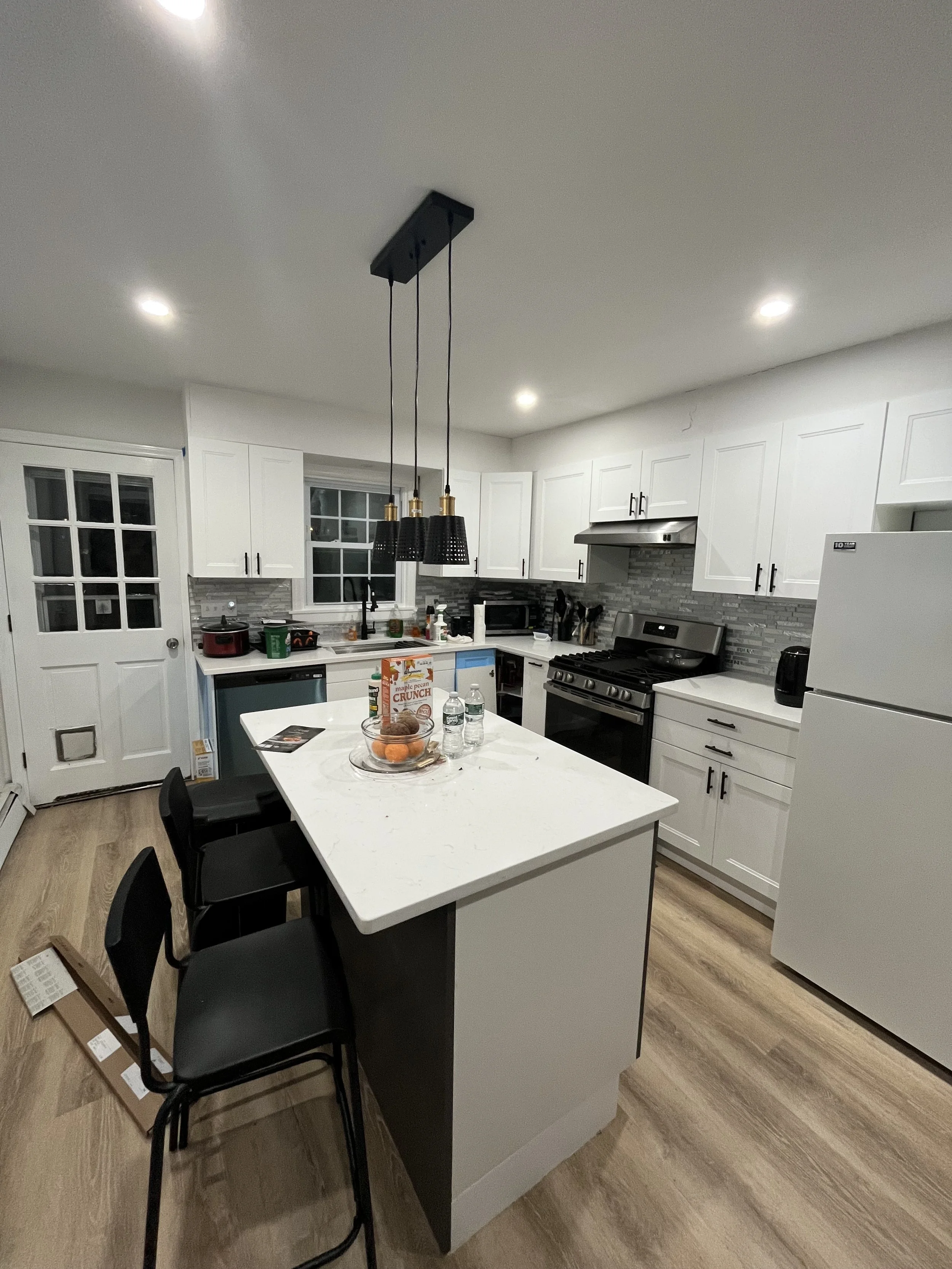 White cabinets, Arctic White countertop, glass mosaic backsplash, matte black fixtures