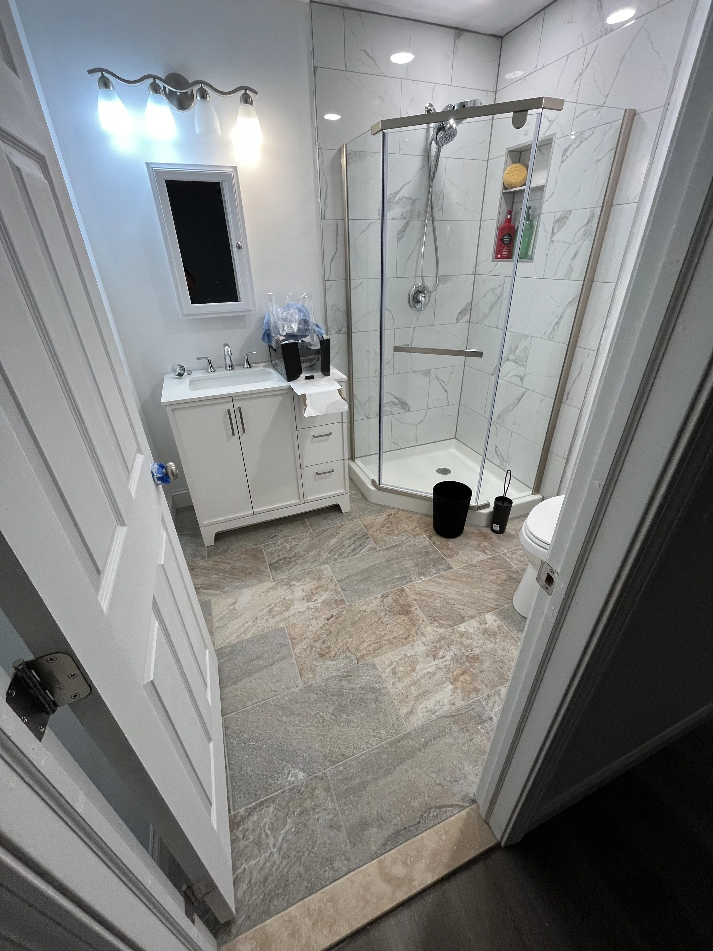 Bathroom with Statuario tile, Belmont floor tile, corner shower, chrome fixtures