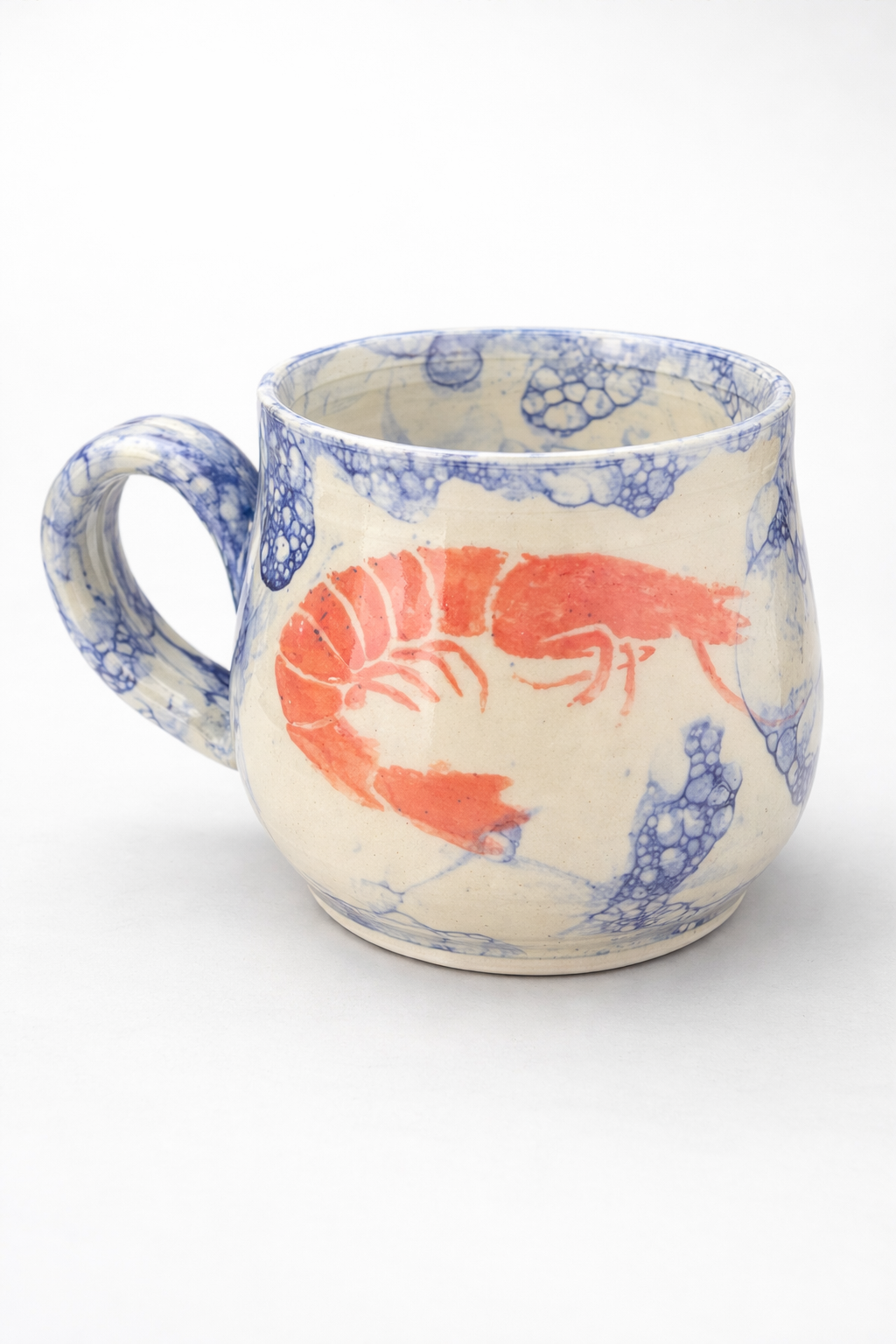 Ceramic mug with red shrimp and blue bubble patterns on a white background.
