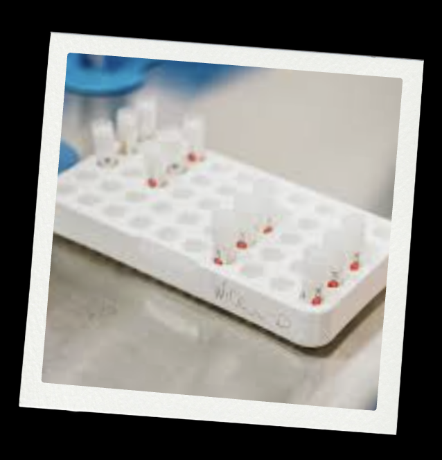 Medical test kit with multiple test strips and vials, placed on a white tray with a handwritten label.