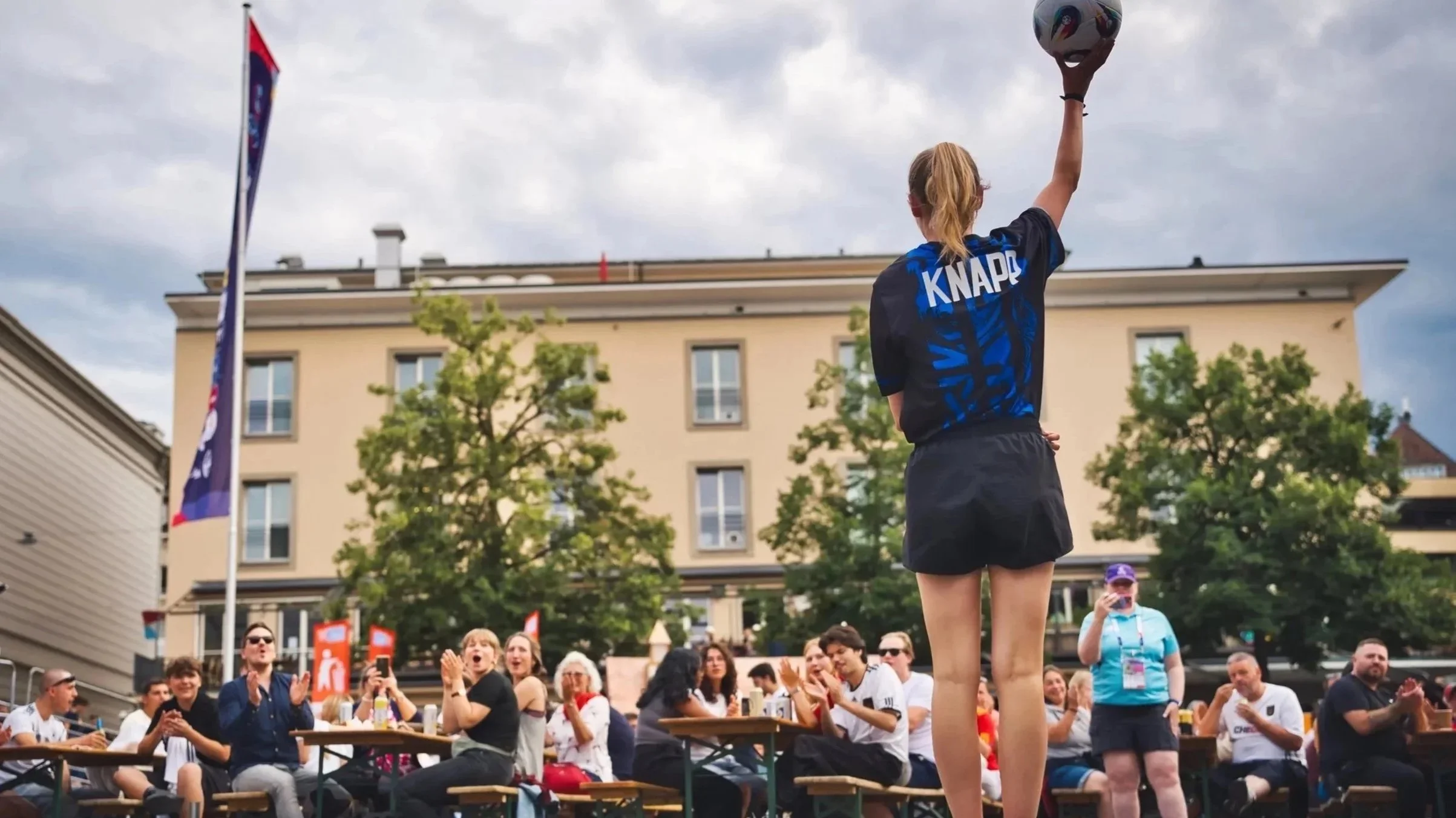 Junge läuft mit einem Fußball in der Hand vor einer Zuschauergruppe bei einem Event