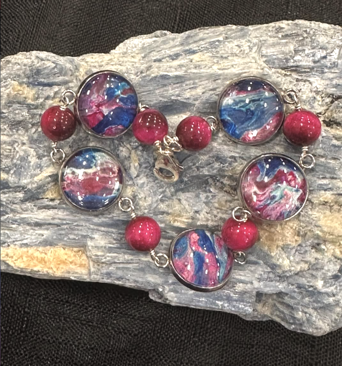 closeup photo of a magenta bracelet with round beads and paint swirl beads as an example of a happy place with nancy jewelry