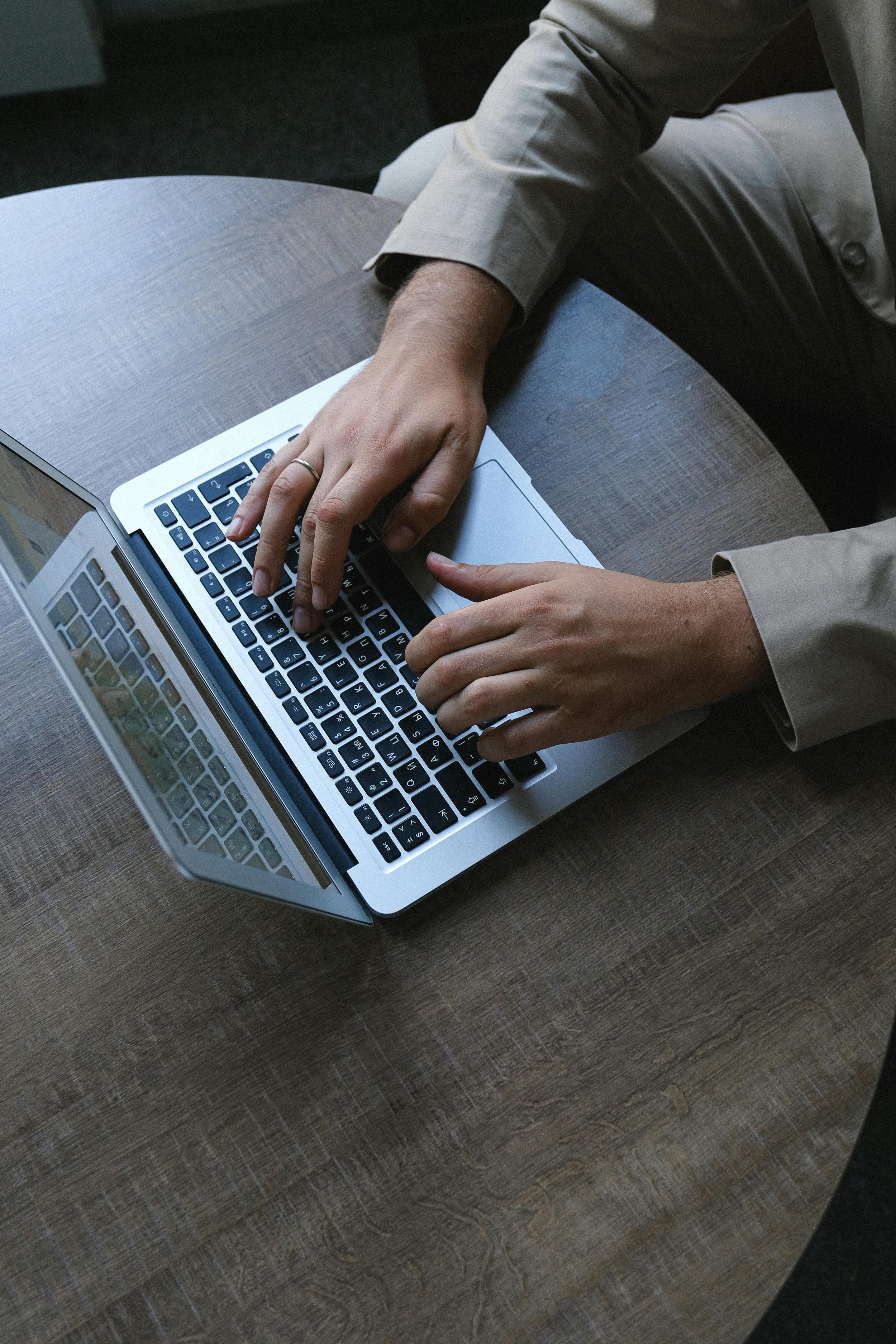 Person using a laptop on a wooden table.