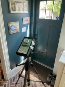 A landline telephone on a tripod stand, positioned near a blue door with window panes and framed pictures on the wall.