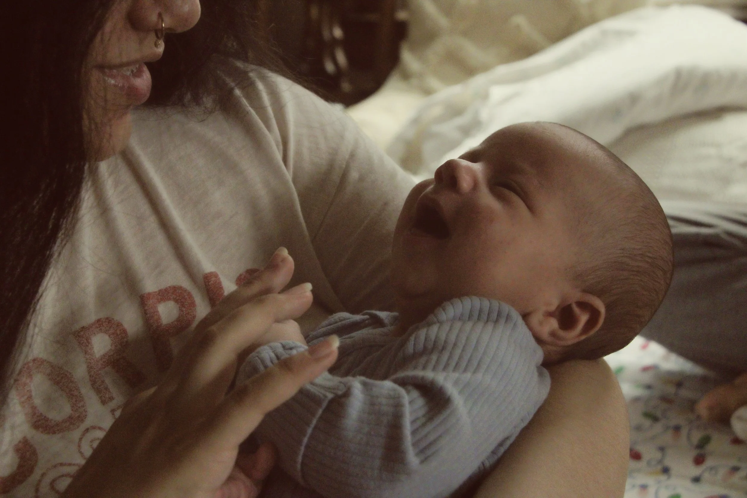 Mother cuddling a sleeping newborn baby in a softly lit bedroom