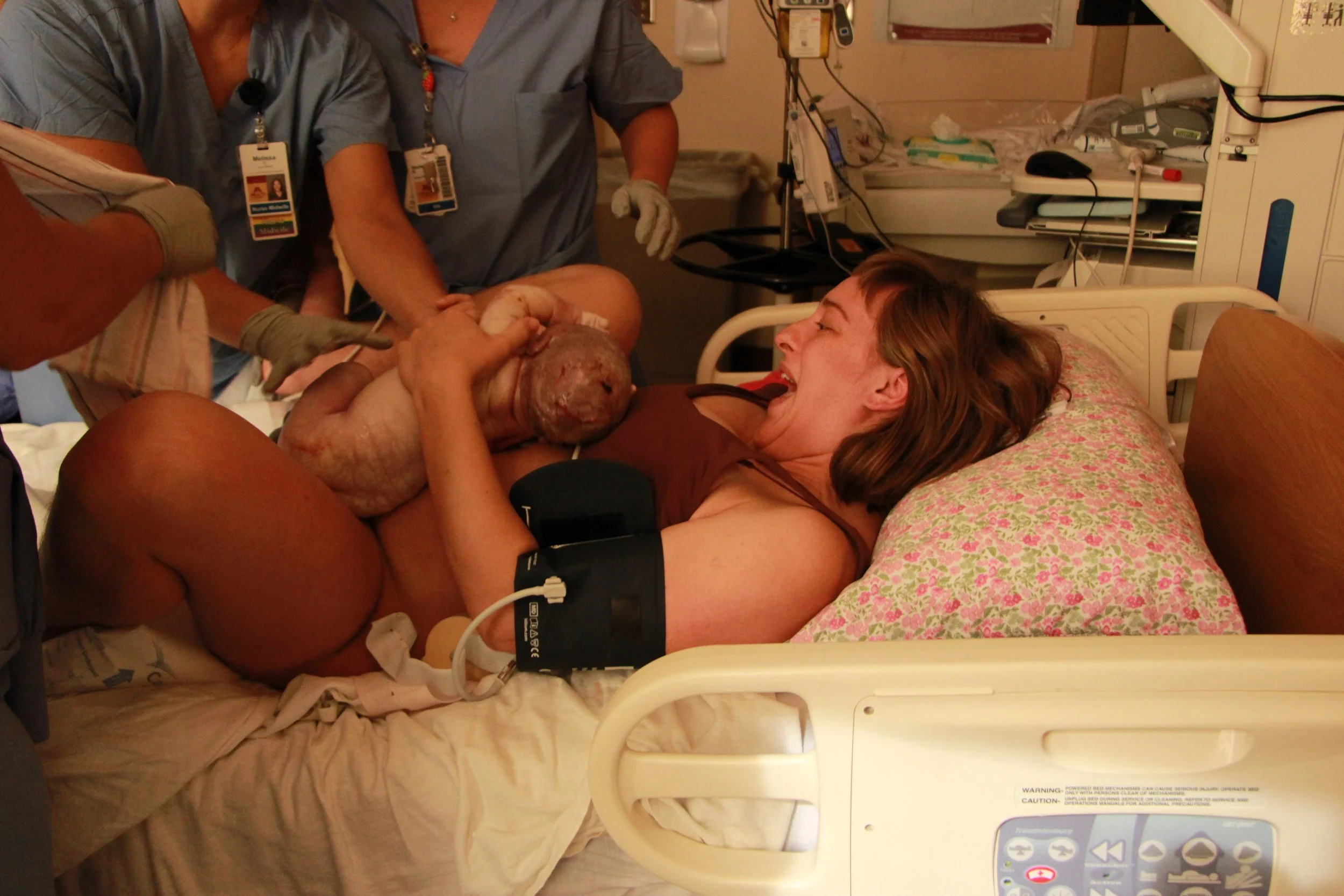 Mother and newborn baby receiving post-delivery care from medical staff in a hospital bed