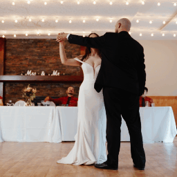 A bride and groom dance together at their wedding reception in a decorated venue.
