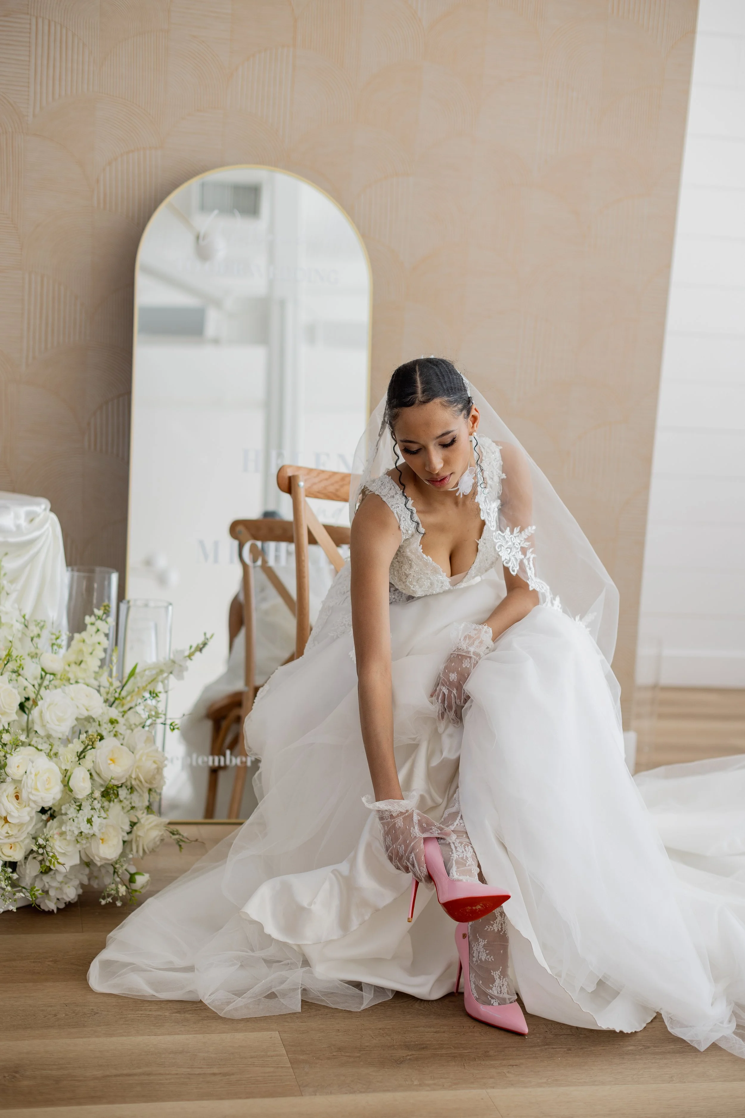 Bride trying on a pink high heel shoe in a bridal studio.