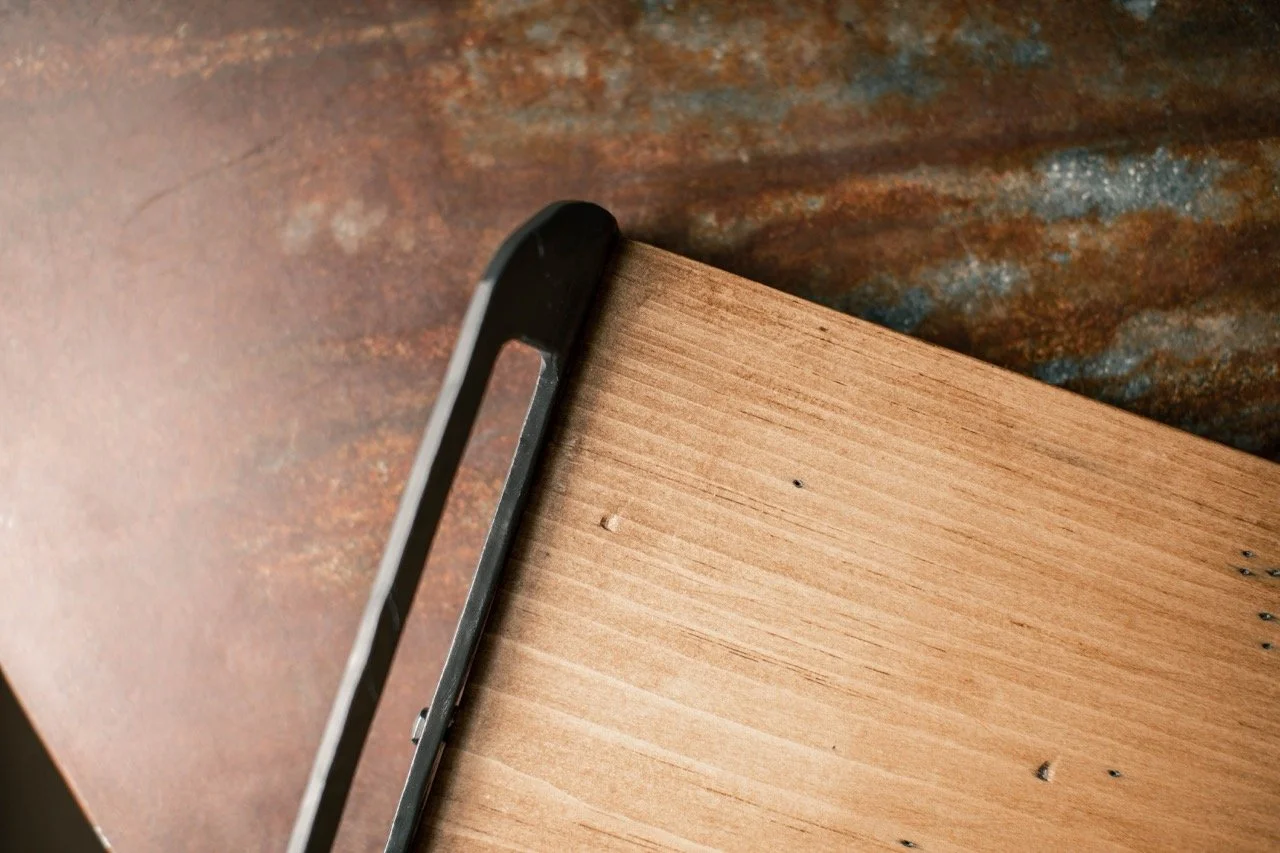 Close-up of a smartphone placed on a wooden surface next to a rusted metal surface.