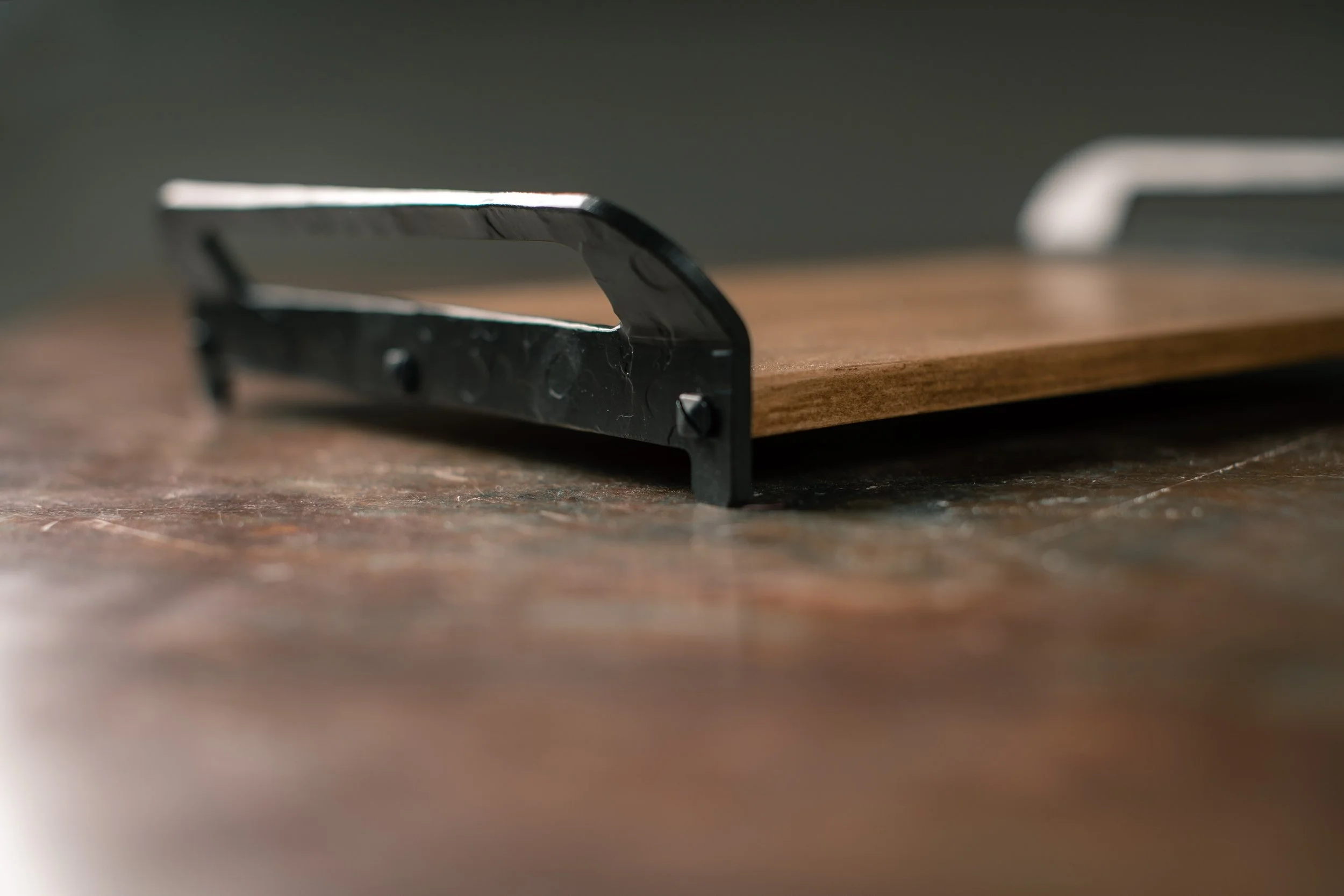 Close-up of a pizza cutter with a black handle and silver blade resting on a wooden surface.