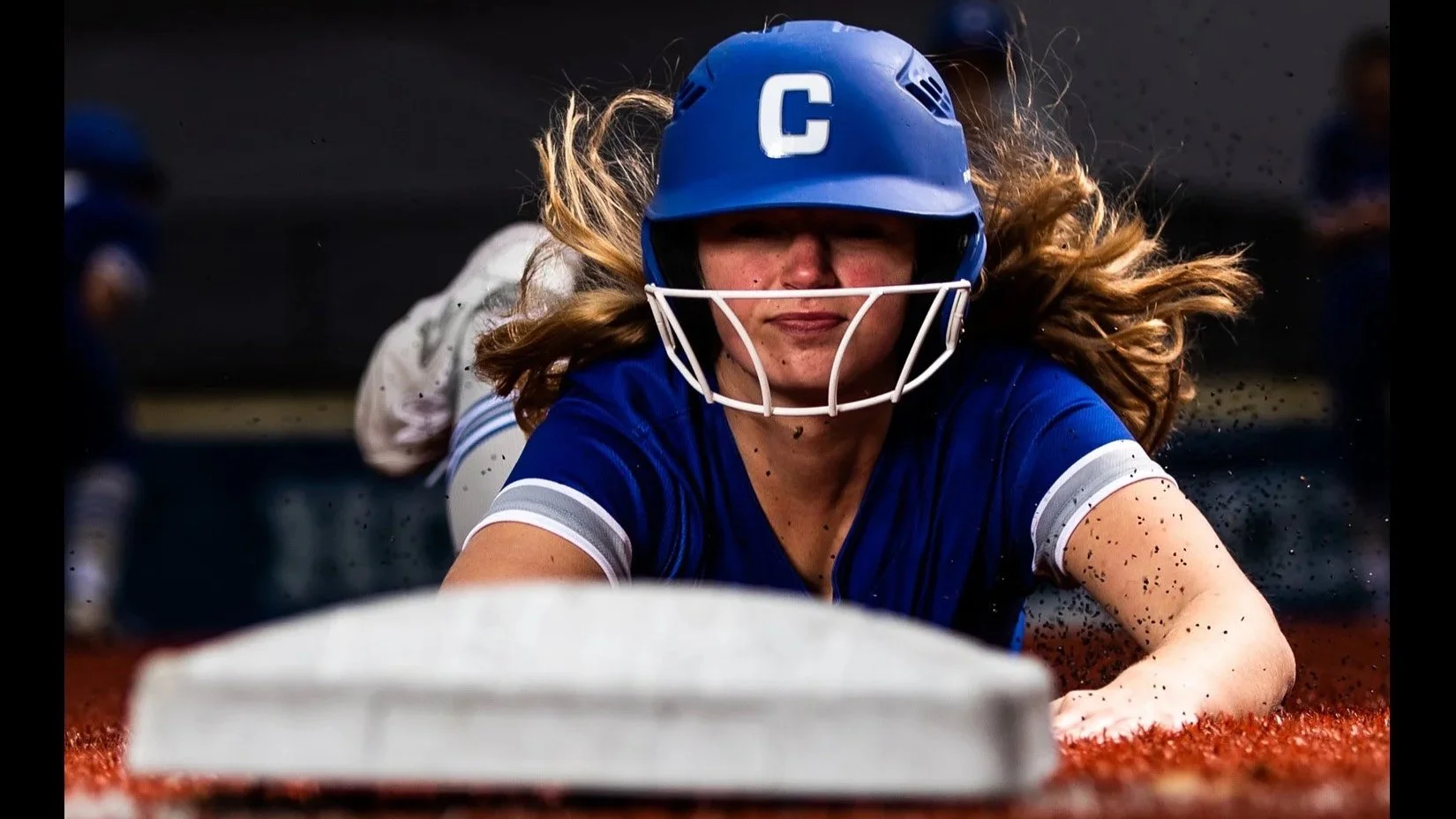 Softball player slides into base facing camera.