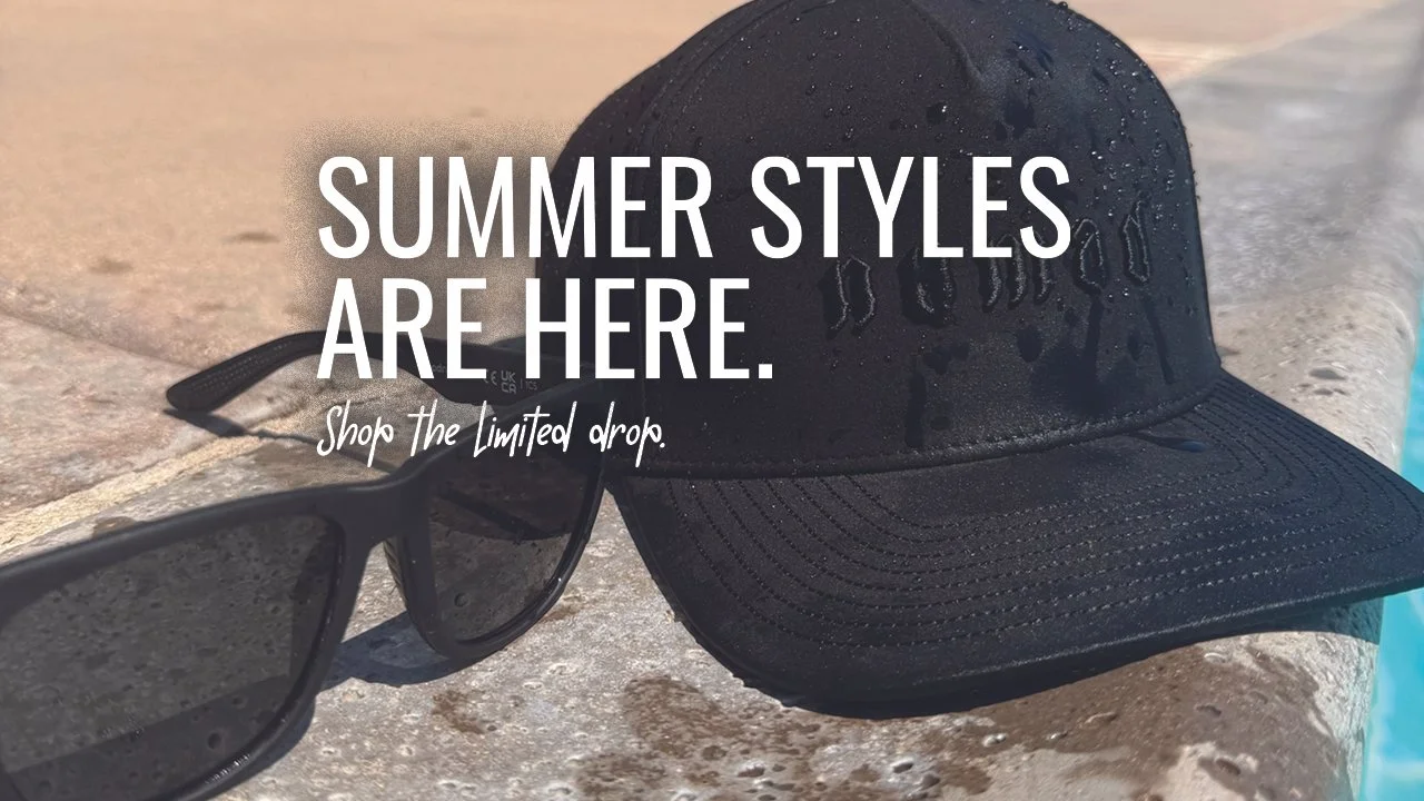 A black baseball cap and a pair of sunglasses resting on a poolside surface with water droplets on the cap. The text overlay reads 'SUMMER STYLES ARE HERE. Shop the Limited drop.'