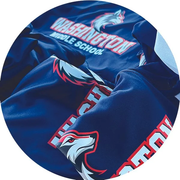 Close-up of a pile of navy blue clothing with Washington Middle School logos and a hawk mascot design.