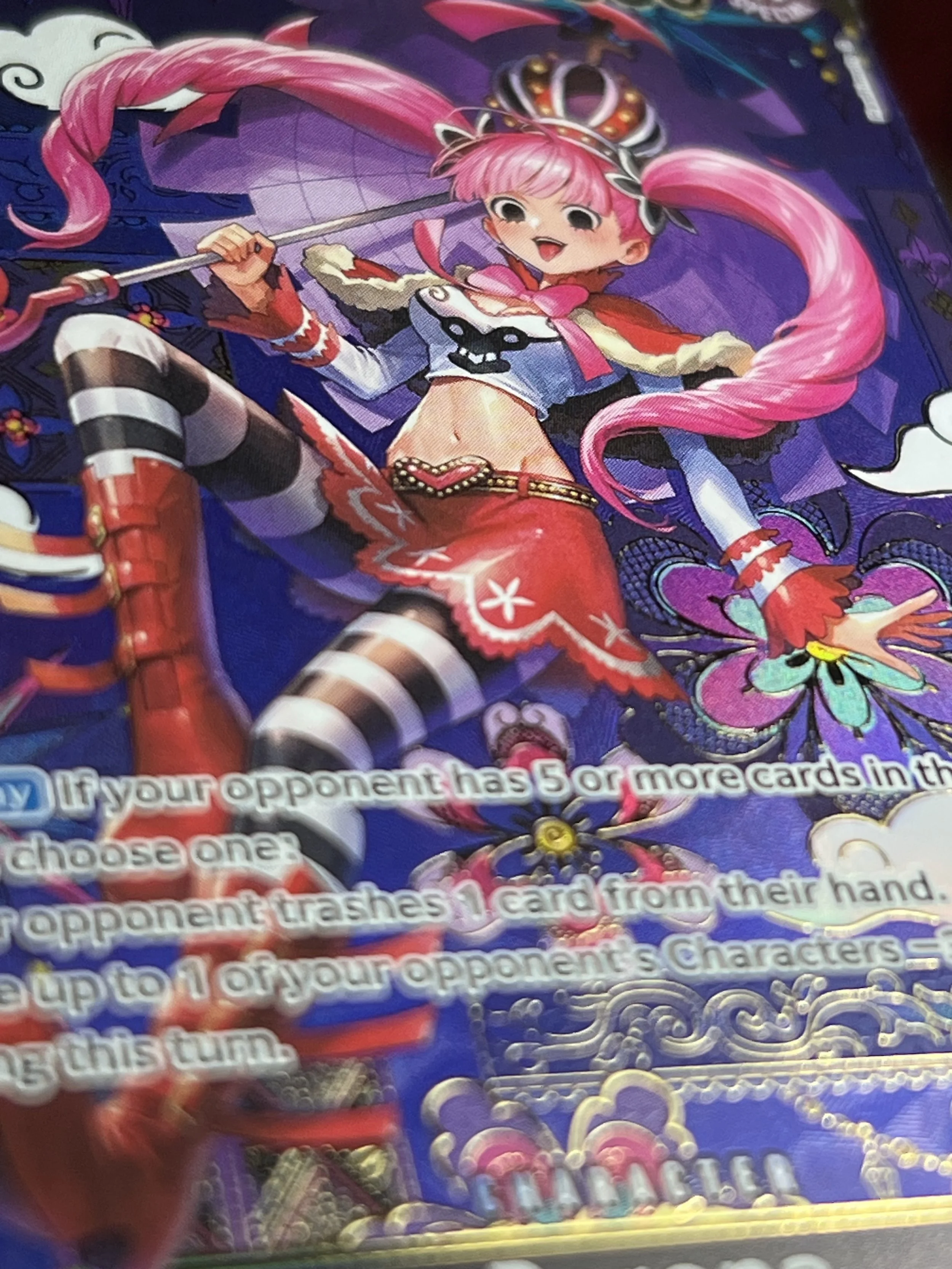 Anime-style illustration of a girl with pink hair, wearing a crown, a cropped top with face design, red skirt, striped thigh-high socks, and red boots, holding a staff with a pink heart-shaped top, surrounded by vibrant purple and colorful decorative elements.