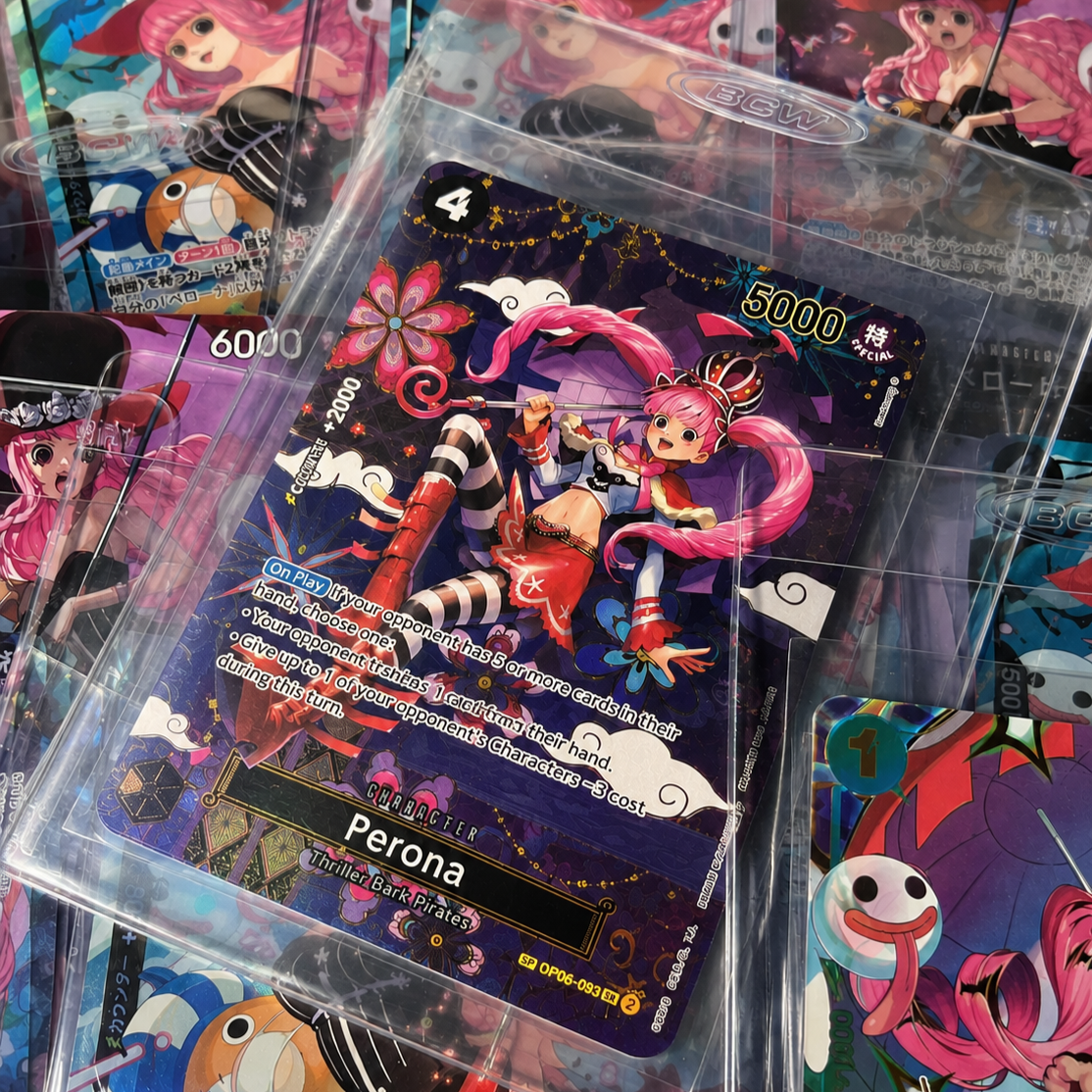 A fantasy-themed trading card featuring a pink-haired girl with twin ponytails, dressed in colorful, playful attire, sitting on a cloud with a Japanese-inspired design. The card has various game-related numbers and text, including the name 'Perona' and the description 'Thriller Bark Pirates.' Other cards with similar anime-style artwork are visible in the background.