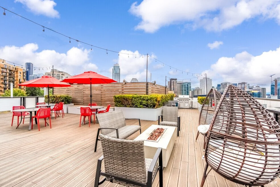 The Rooftop of the Cove apartments on Capitol Hill in Seattle, Washington featuring umbrellas, outdoor furniture, and city skyline views
