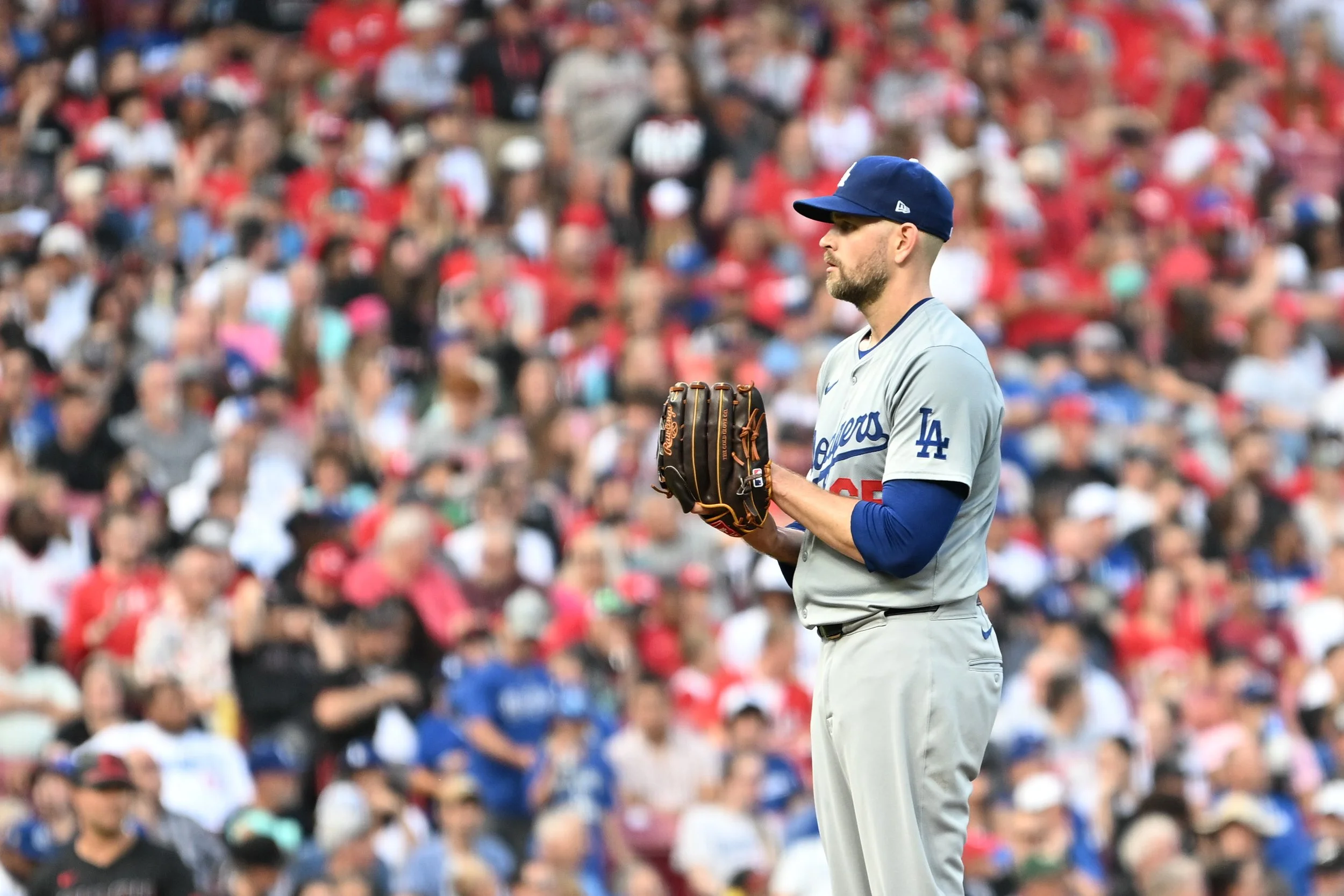 A baseball player in a Dodgers uniform standing on the field with a baseball glove, in front of a large crowd of spectators.