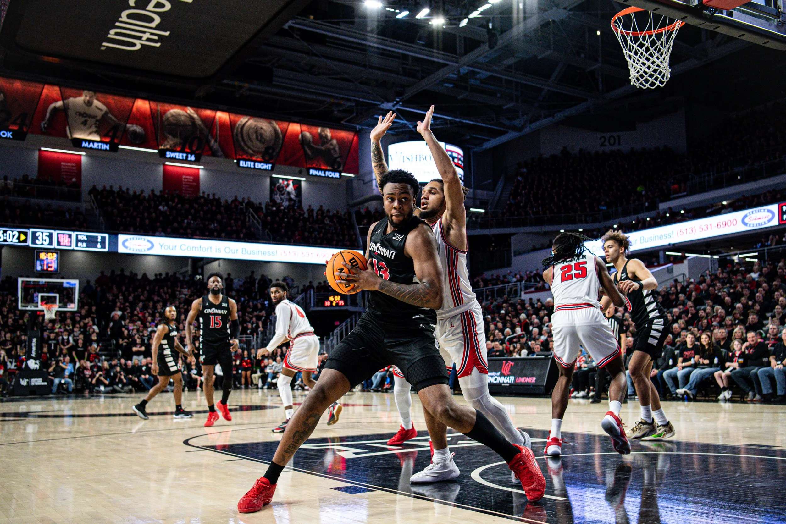 Basketball game in progress with players on the court, audience in the stands, and scoreboard displaying 35-19 with 5:02 remaining.