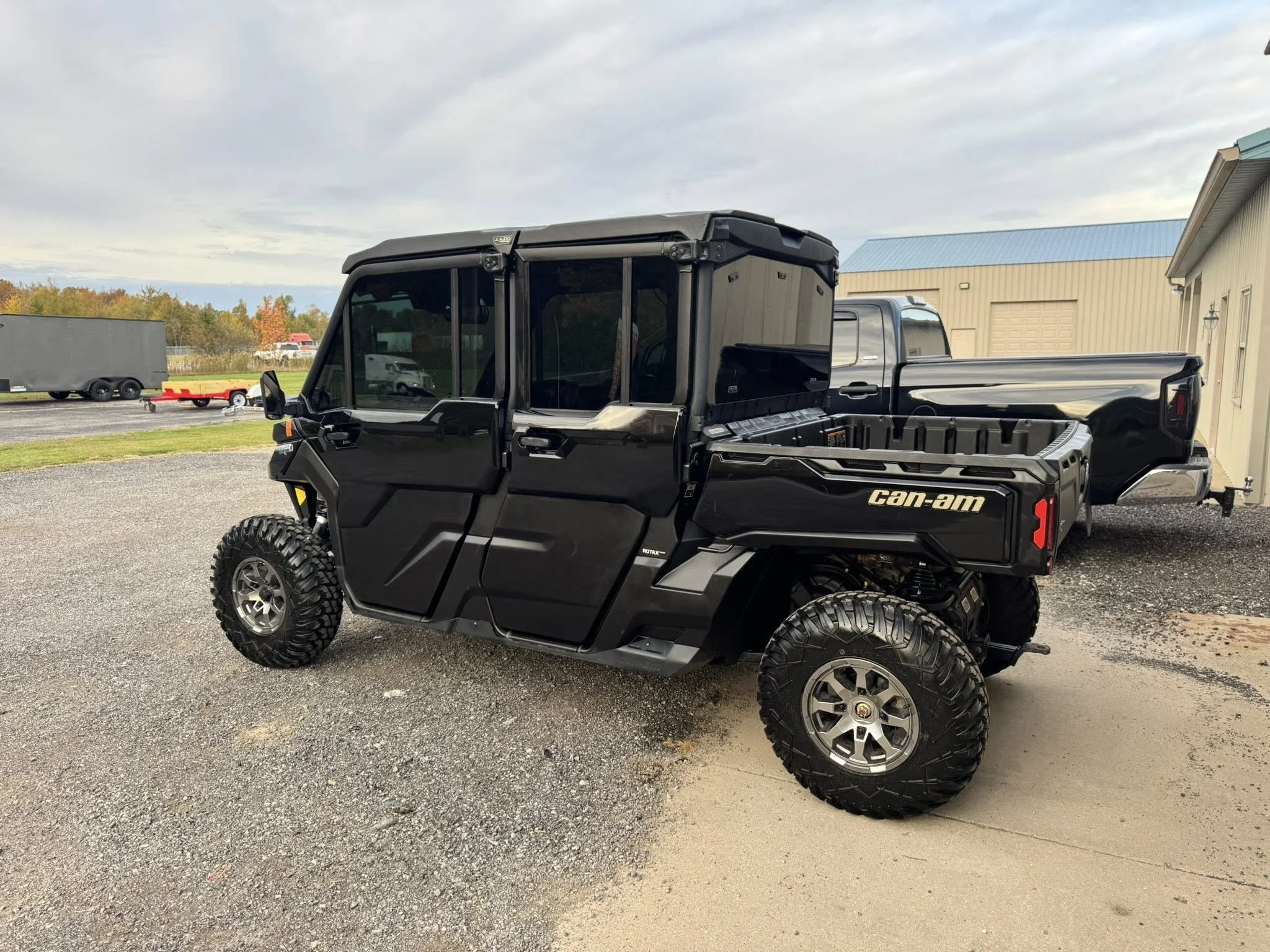 Black Can-Am off-road utility vehicle parked on gravel outside a building.