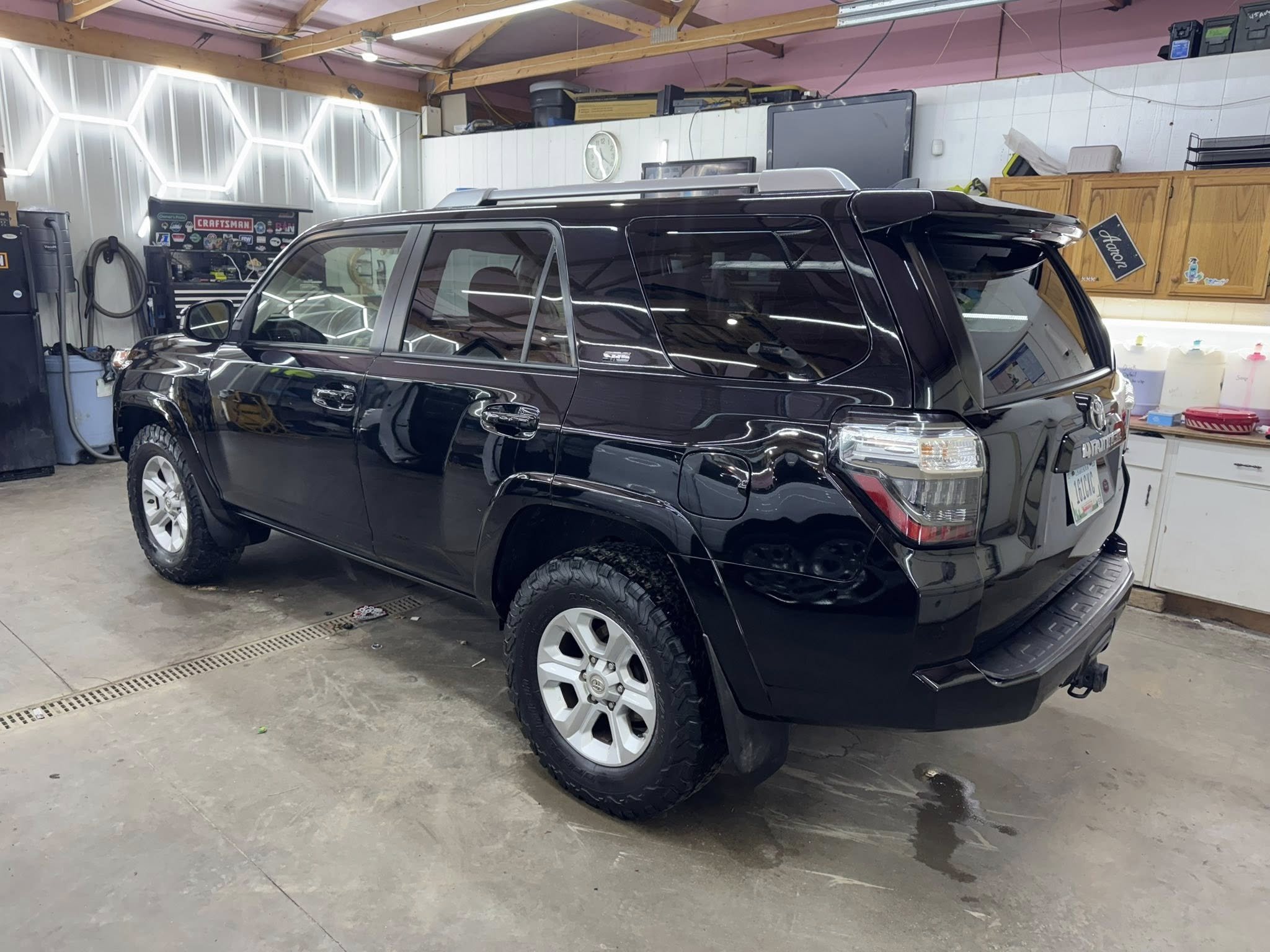 Black SUV inside a garage with tools, storage cabinets, and decor on the walls.