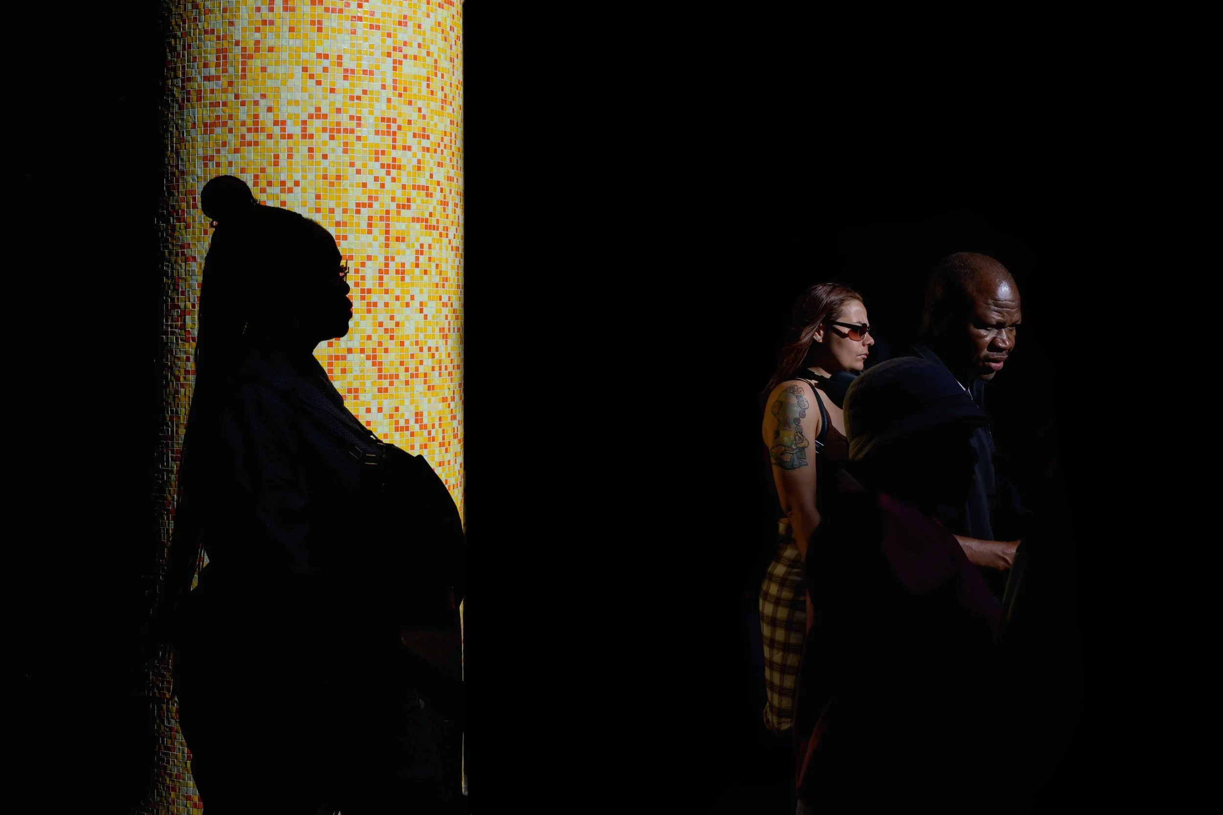 Colour photo taken by Donna Lancia in Rome of outside a Metro station.  A woman is in deep shadow and a couple is highlighted in the bright sunshine in the style of chiaroscuro. 