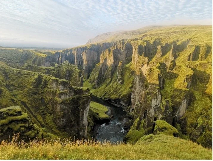 Paisaje natural con cañones profundos, río en el fondo, vegetación verde y cielo con nubes dispersas.