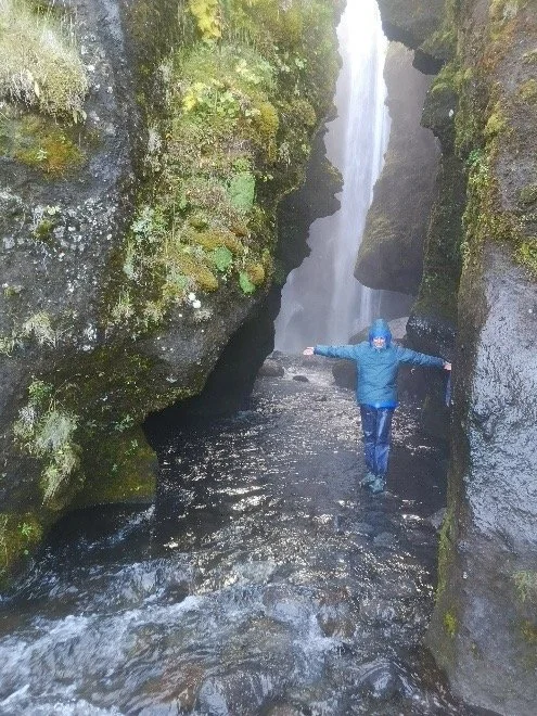 Persona con ropa impermeable en un cañón con cascada y agua corriente.