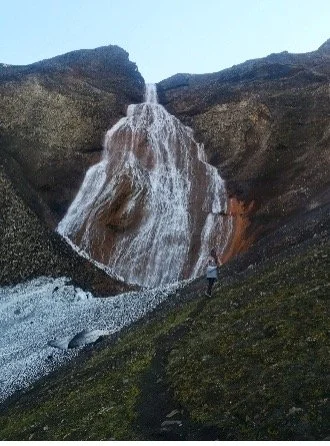 Persona observando una cascada en un paisaje montañoso.