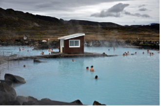 Persona disfrutando en una piscina al aire libre en un día nublado, con colinas y cielo gris en el fondo.