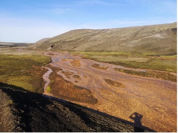 Pantano arenoso en un paisaje montañoso con un cielo despejado.