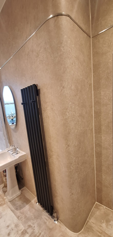 A modern bathroom corner with a black vertical radiator, a small round mirror, and a white pedestal sink.