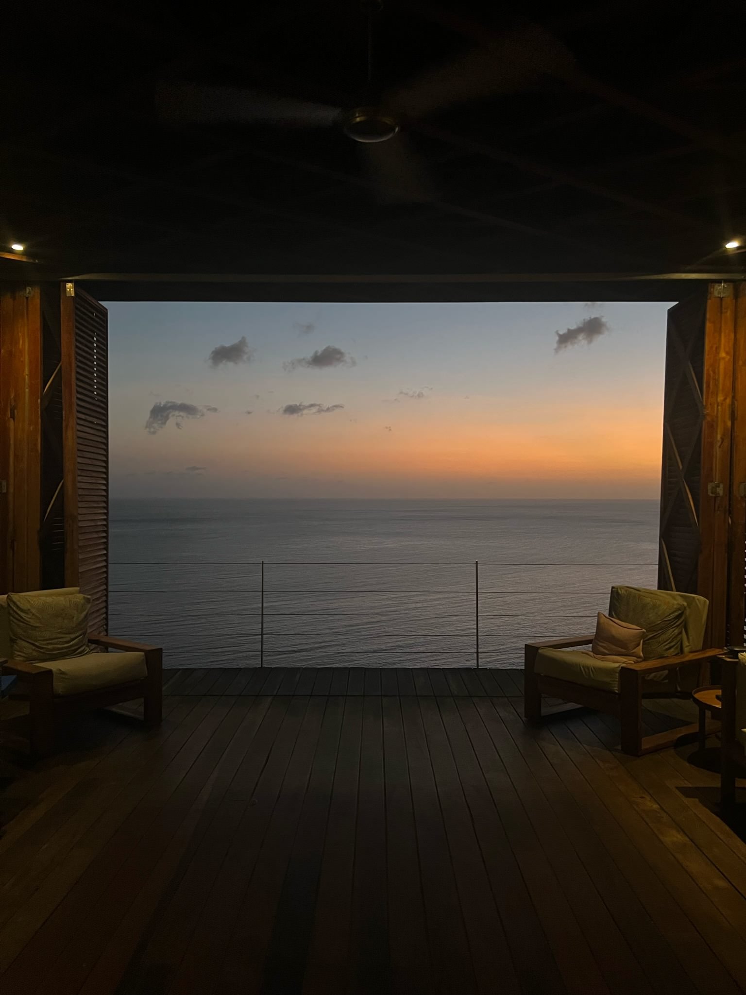 Two chairs in front of an open-air view of the ocean at sunset