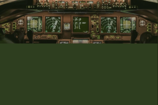 The image shows the cockpit of an airplane with multiple control panels, screens, and various instruments.