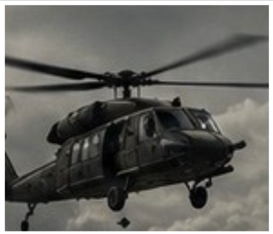 Military helicopter in flight against cloudy sky.