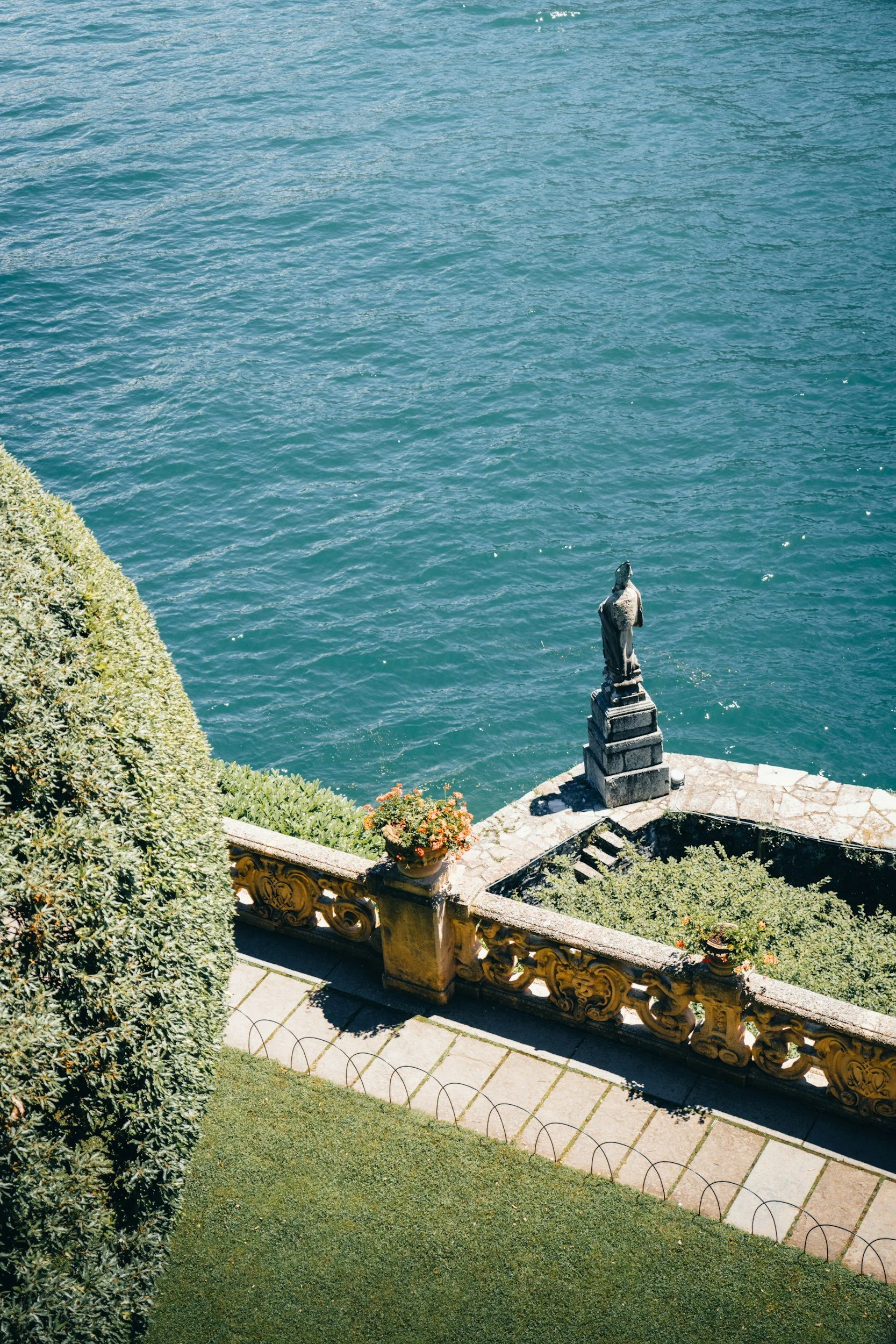 A scenic view of a large lake with mountains on both sides under a partly cloudy sky during sunset.