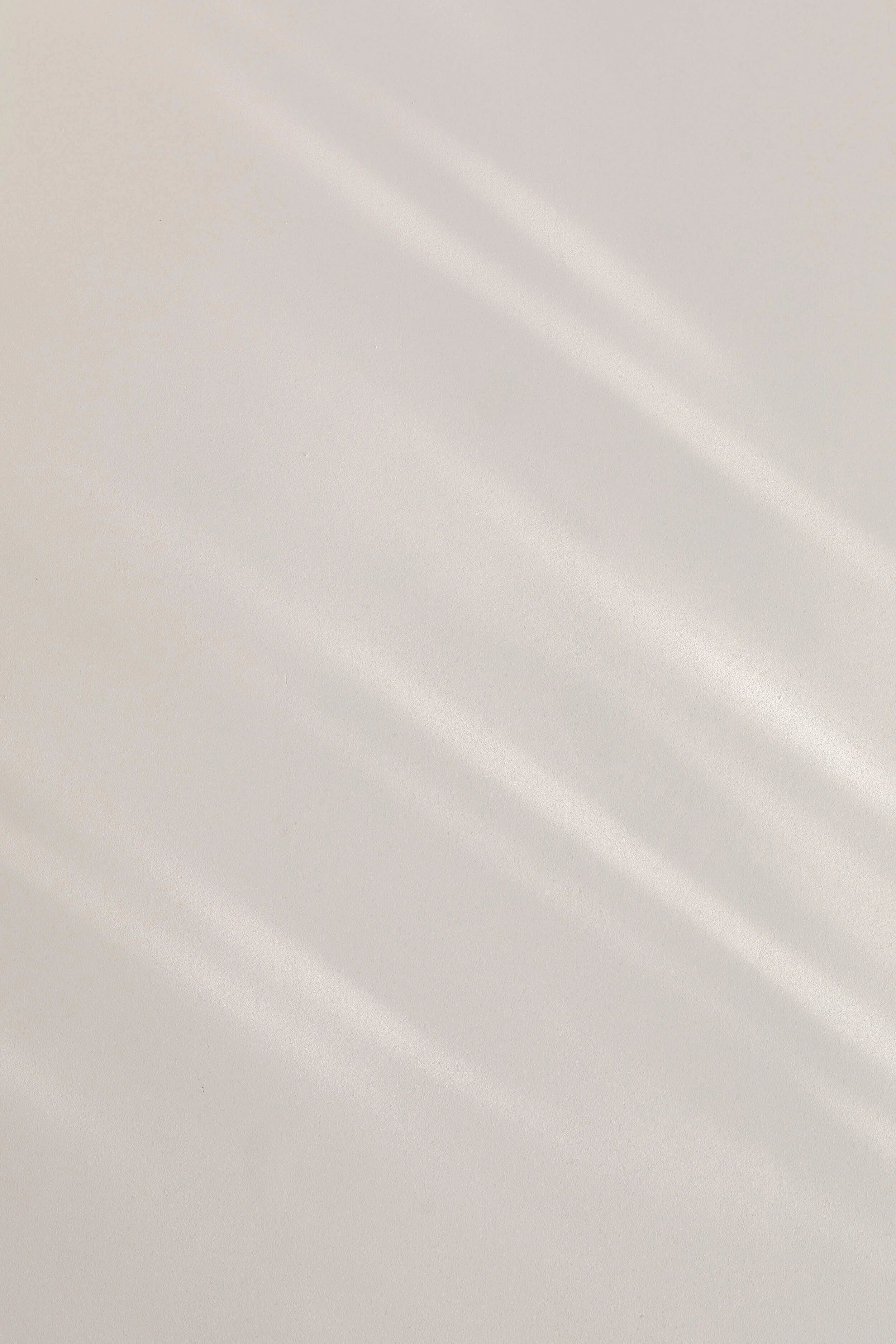 Smooth, light-colored surface with soft diagonal light reflections.