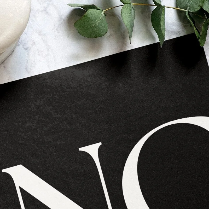 A close-up of high-contrast brand collateral featuring a bold, white serif 'N' and 'C' on a textured black background.