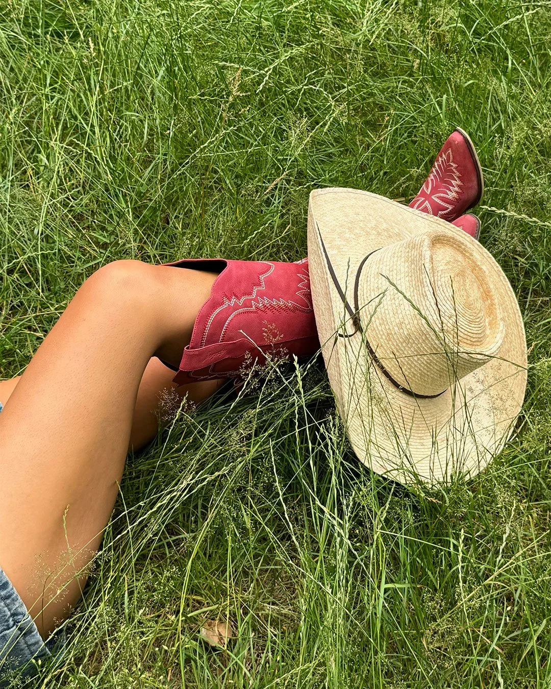 The Prairie palm leaf cowboy hat photographed in long grass with red Western boots for the American Summer campaign.