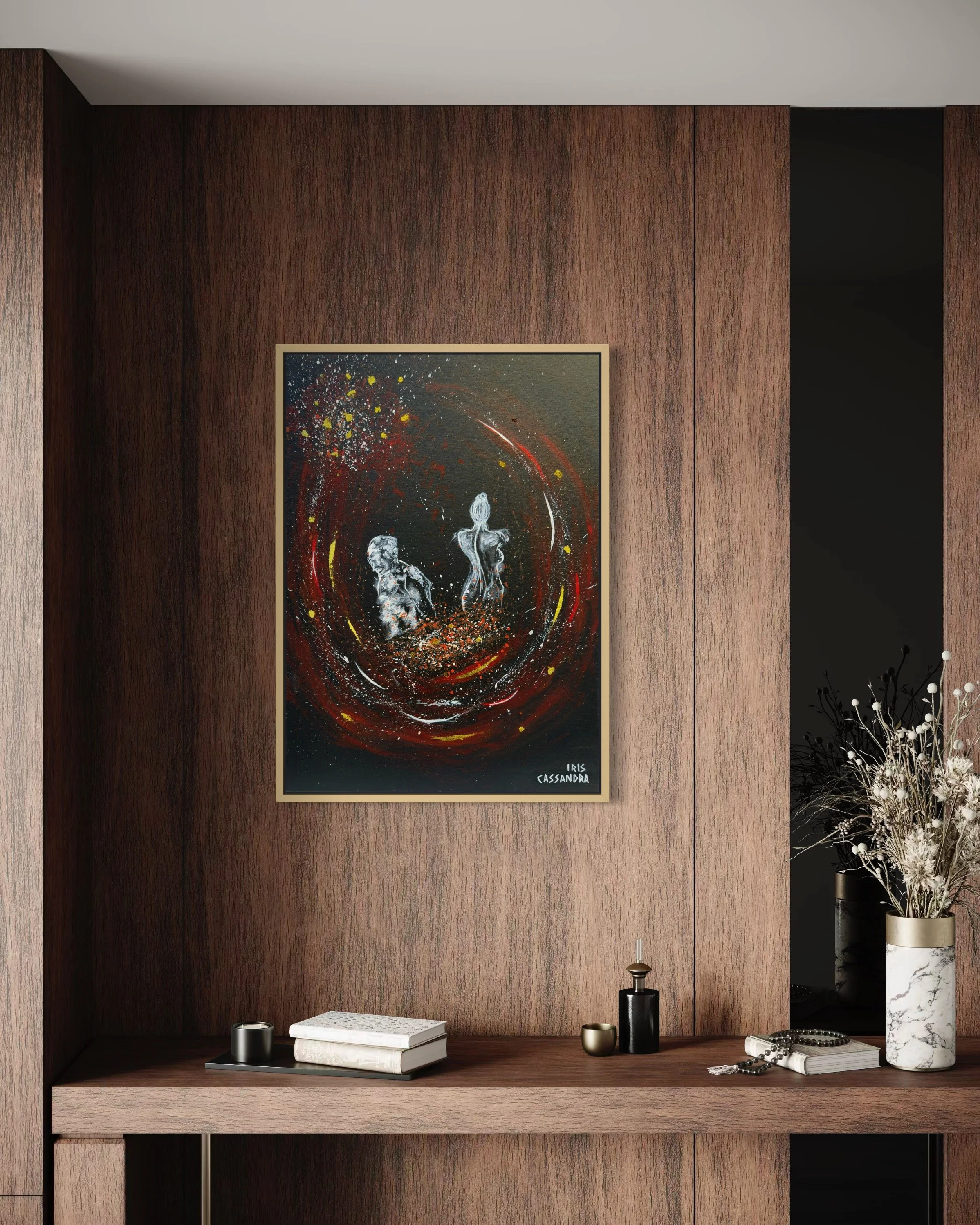 A modern wooden wall with an abstract painting of two humanoid figures surrounded by swirling red, yellow, and white splashes. A shelf below holds books, candles, and decorative objects, with a vase of dried flowers to the right.