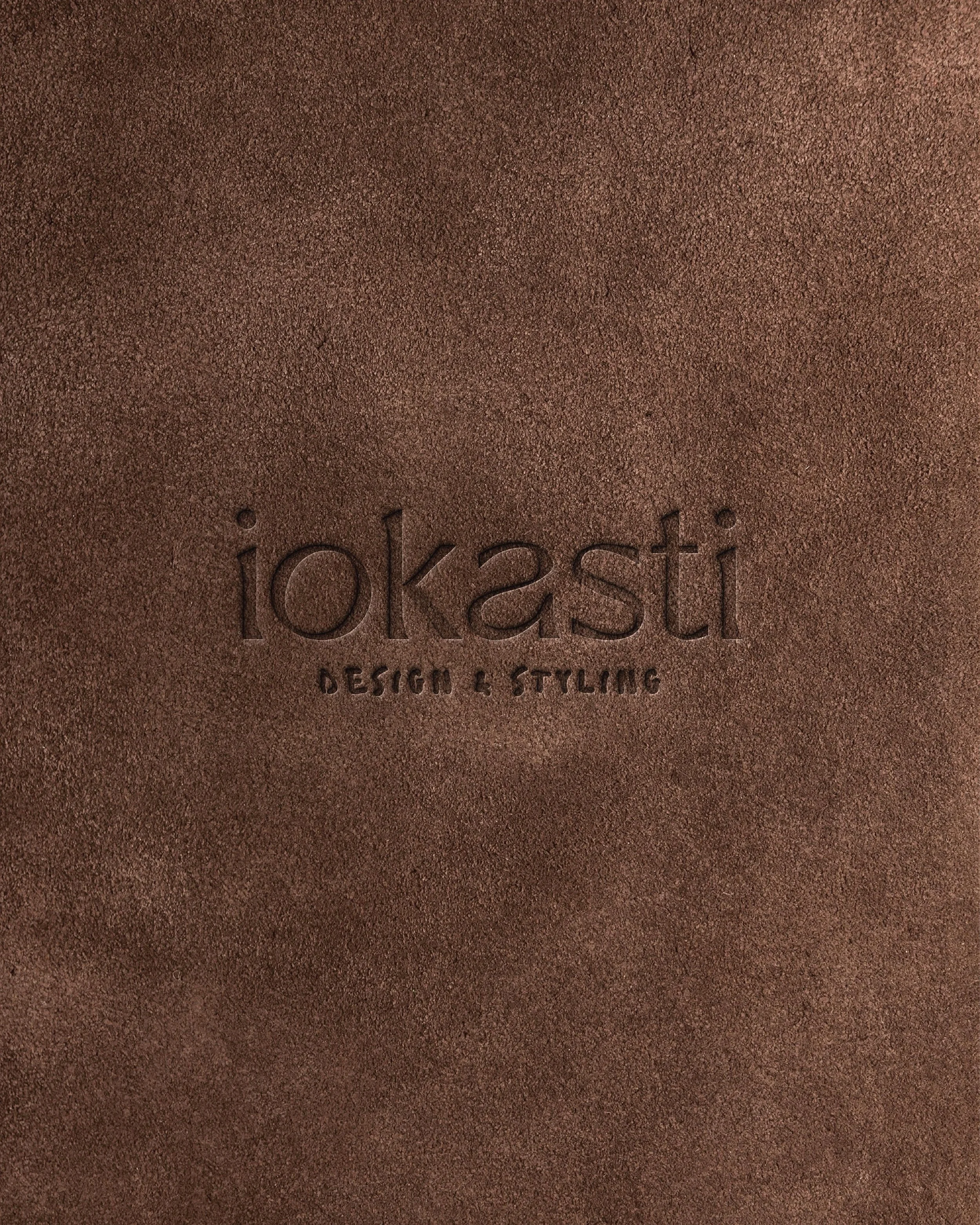 Close-up of a brown textured surface with the words Iokasti DESIGN & STYLING' embossed in the center.