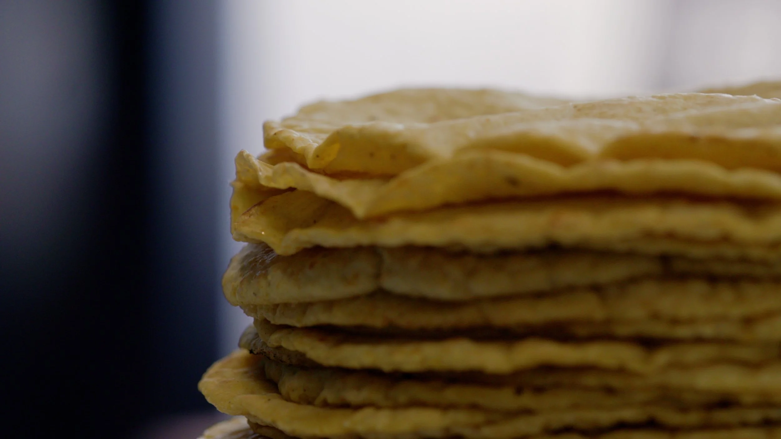 Close-up of a stack of freshly made tortillas on a dark and light background.