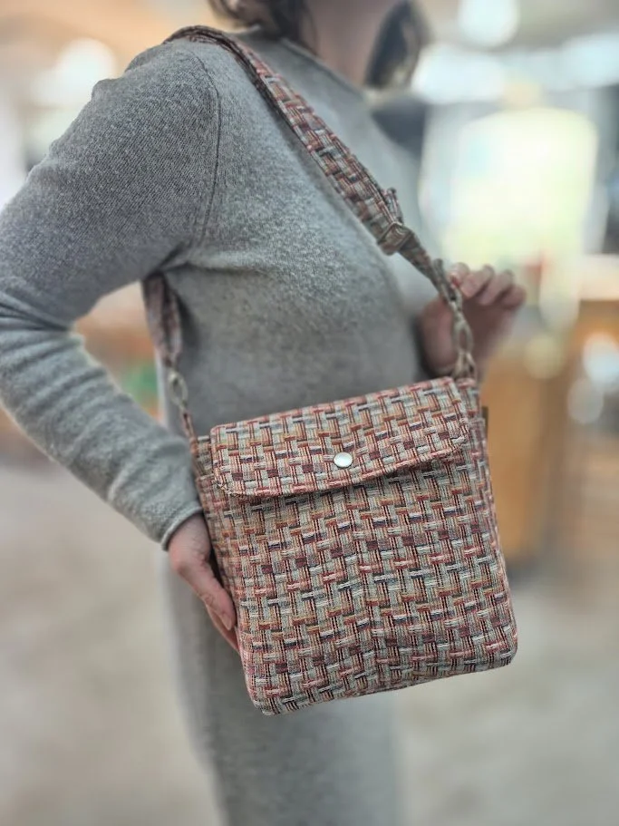 Person wearing a gray sweater with a patterned fabric crossbody bag.