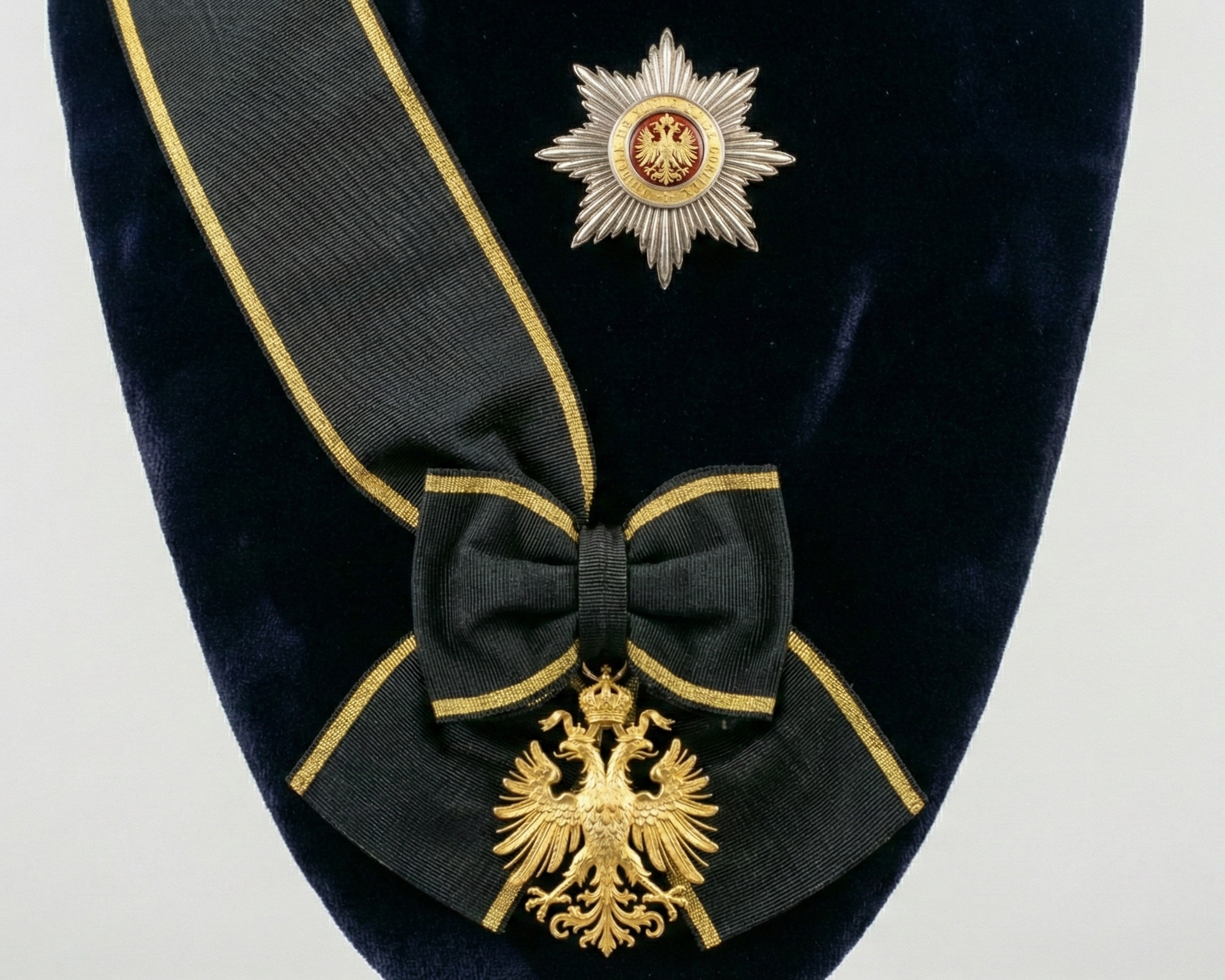 A medal ribbon with a bow, a star-shaped medal, and a gold eagle emblem on a dark fabric background.