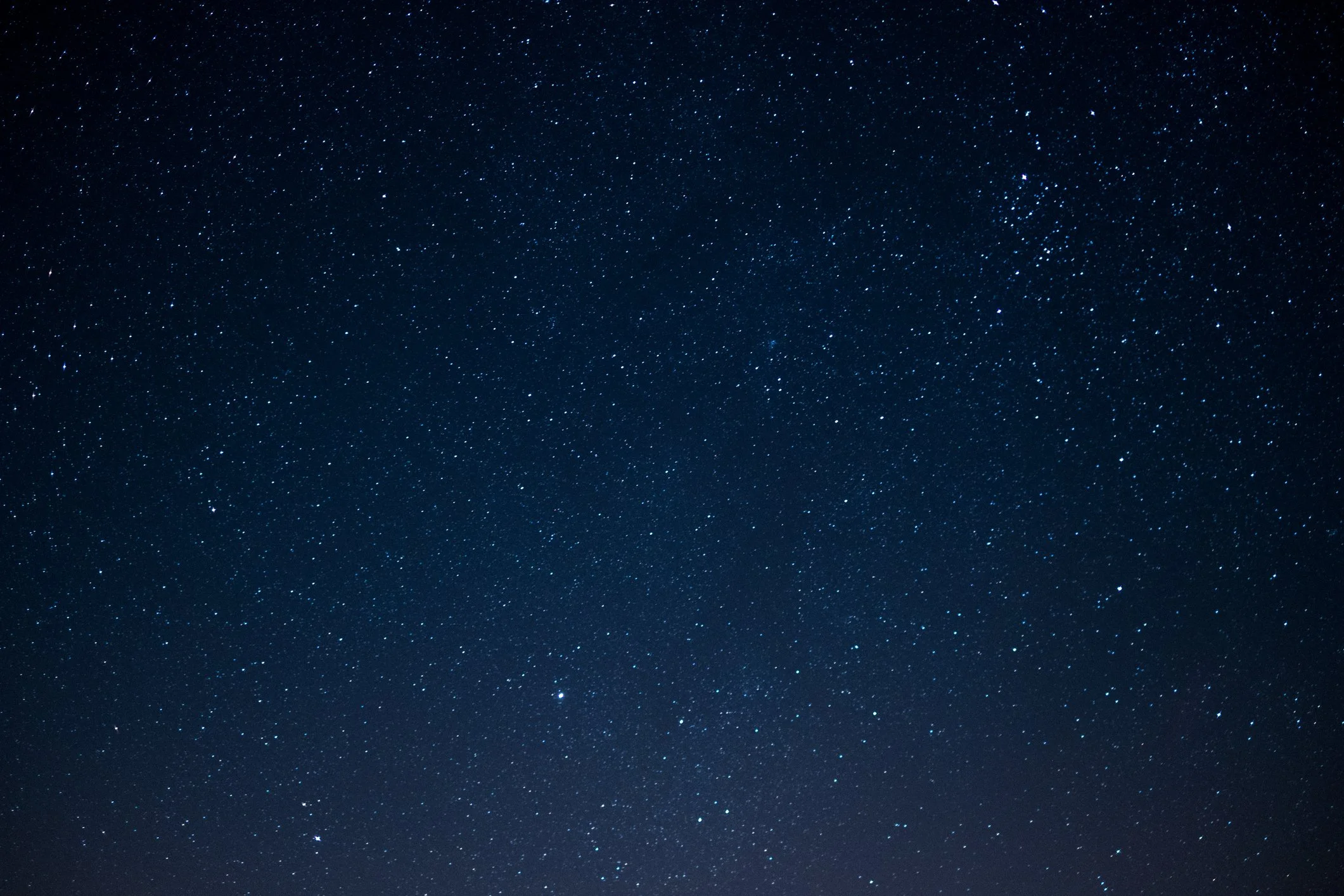 Night sky filled with numerous stars and a faint, blurry Milky Way galaxy