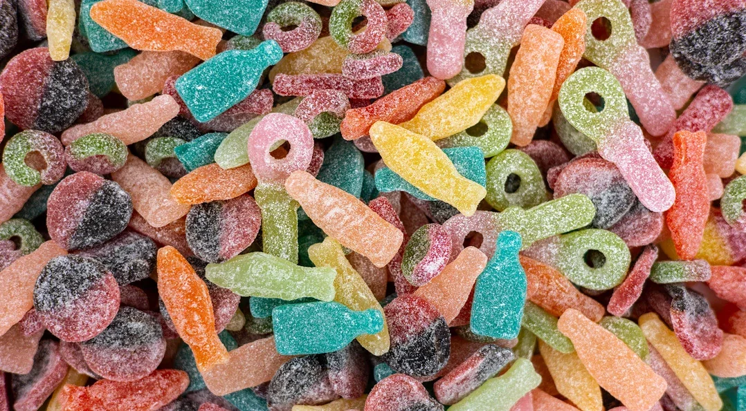 Colorful sour gummy candies in various shapes and colors.