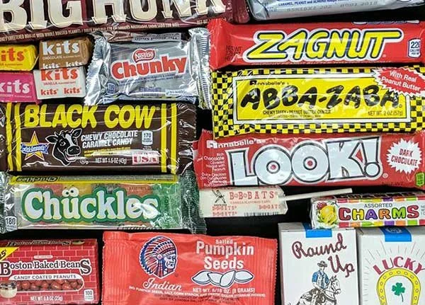A variety of candy bars and snacks including Big Fudge, Zagnut, ABBA-ZABA, Black Cow, Chuckles, Look! chocolate bar, Charms, Boston Baked Beans, Indian Salted Pumpkin Seeds, Round Up, and Lucky.