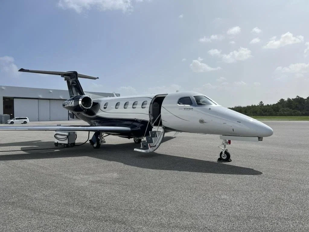 A private jet parked on an airport tarmac with a set of stairs leading into the cabin.