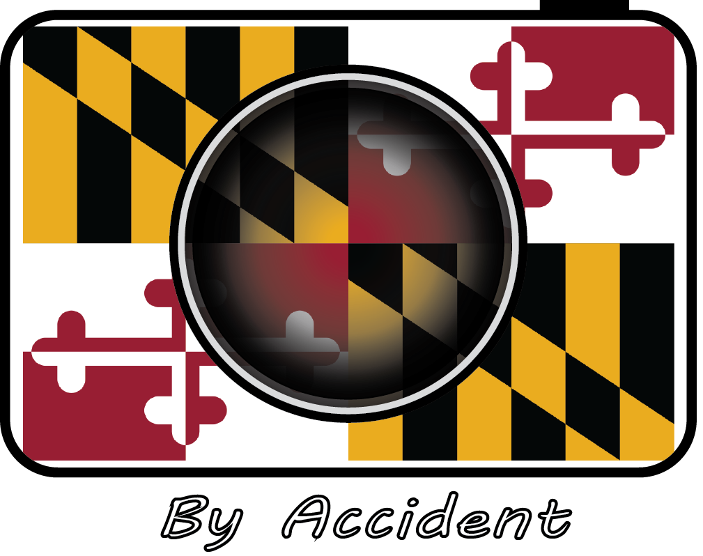 A camera lens overlaying the Maryland state flag with the text 'By Accident' below.