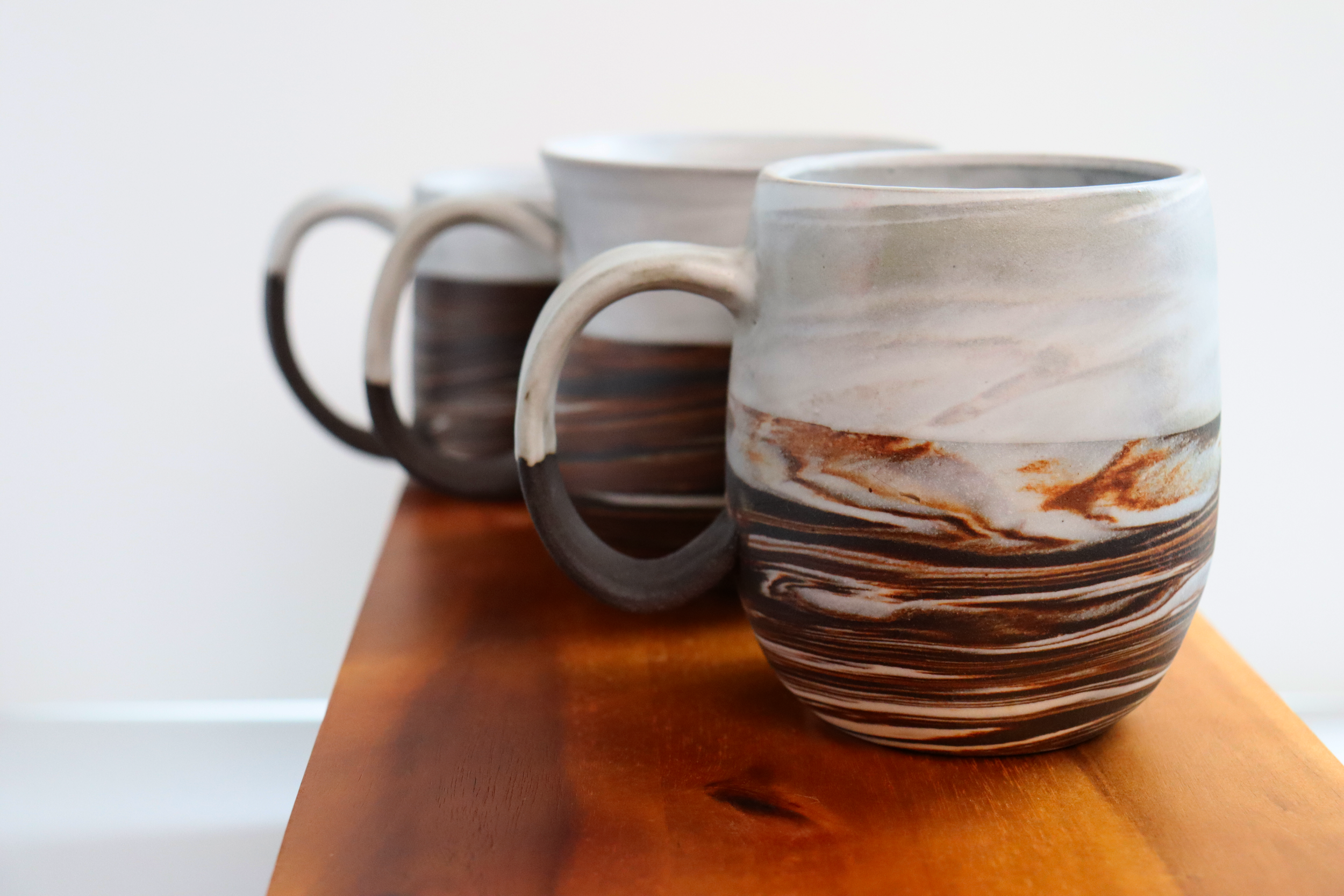 Dark brown stoneware and porcelain marbled mugs with satin white glaze